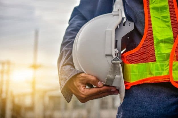 Profissional segurando capacete de segurança em canteiro de obra